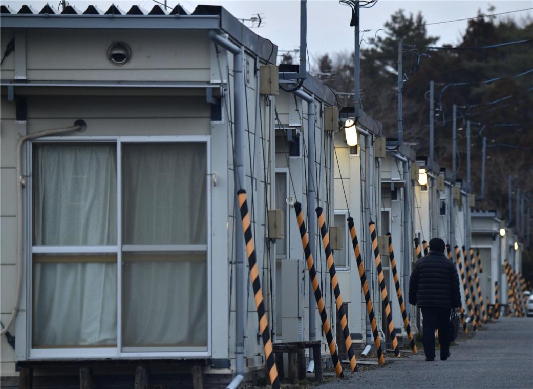 <p>Eine Person geht an temporären Fertigbauwohnungen vorbei. Iwaki, Präfektur Fukushima, gehört zu einer Region, die vom Erdbeben am 11. März 2011 und dem Tsunami im Nordosten Japans betroffen ist.</p>