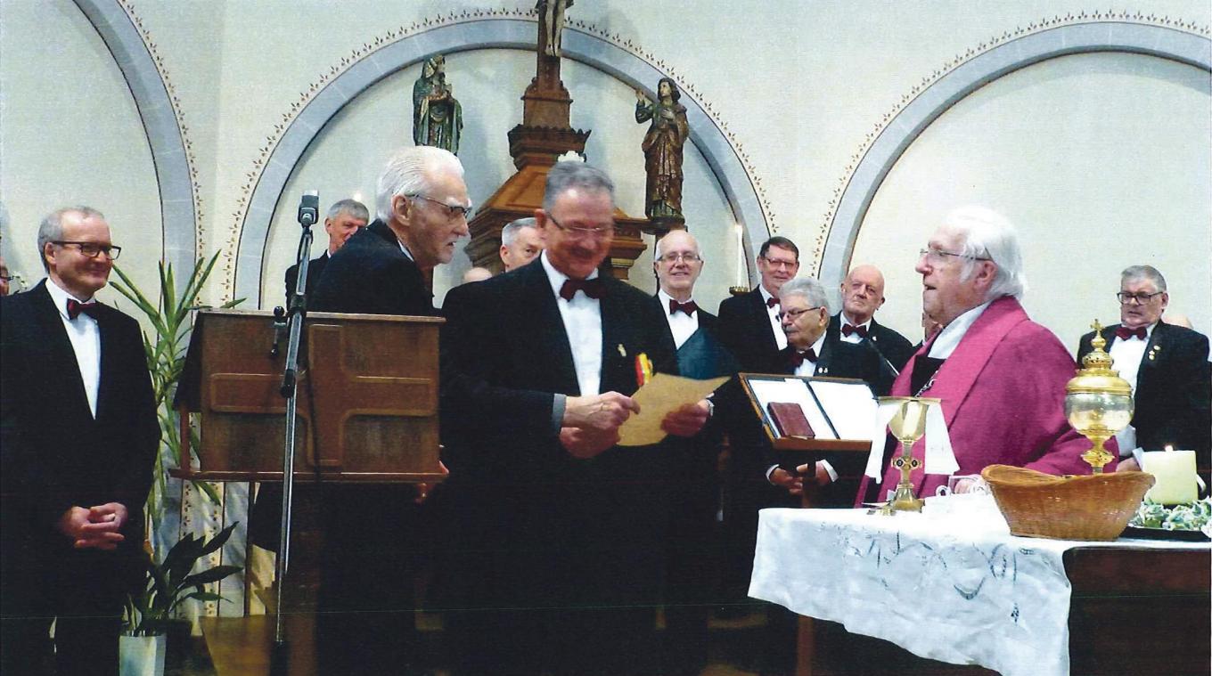 <p>Pastor George Poerter (rechts) überreicht Präsident Edgar Herbrand (Mitte) die vom Bistum Lüttich gestiftete Goldene Lambertus-Medaille für 40 Jahre Kirchengesang.</p>
