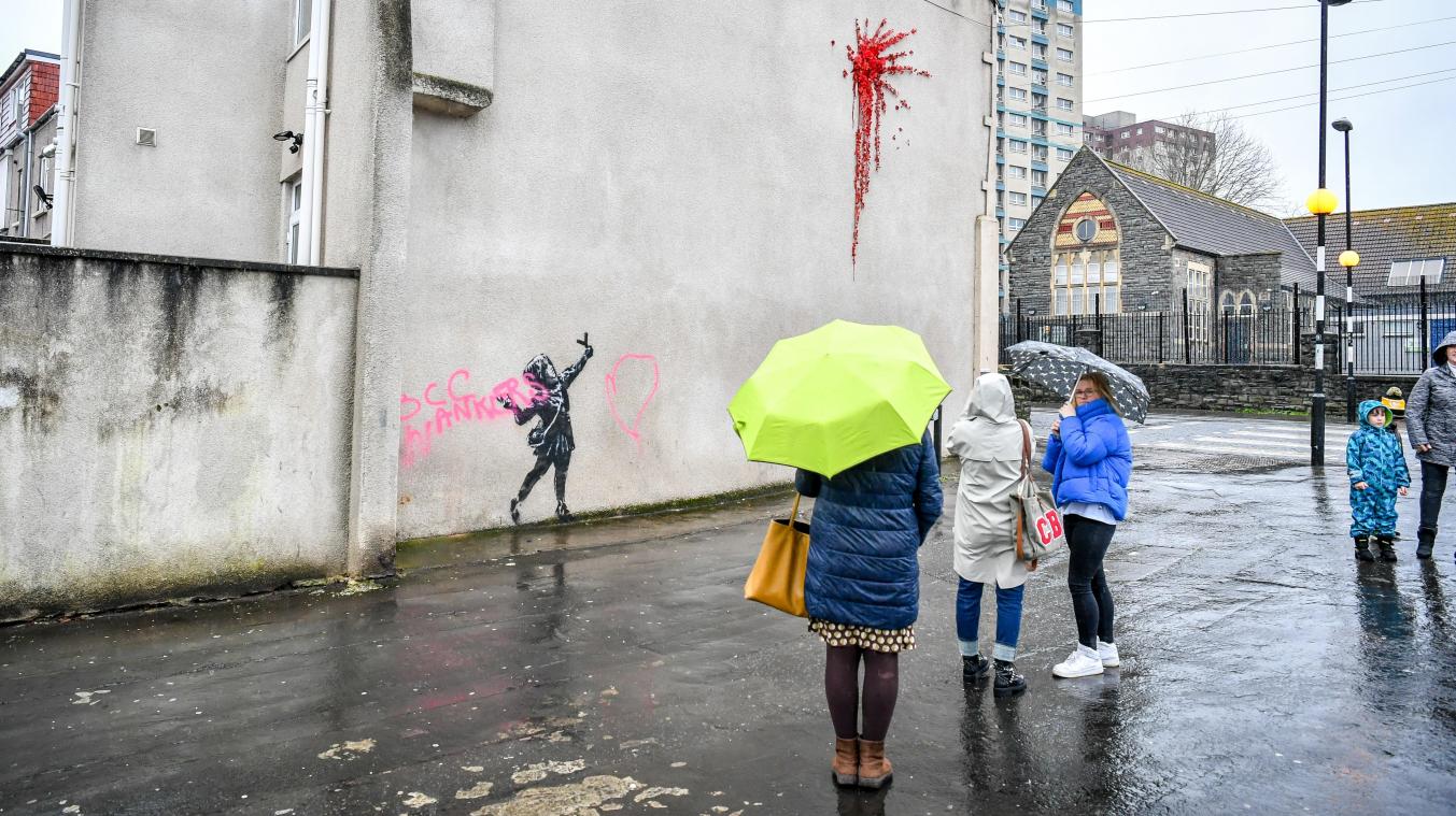 <p>Frauen betrachten das mit rosa Graffiti zerstörte Wandbild des britischen Street Art Künstlers Banksy.</p>