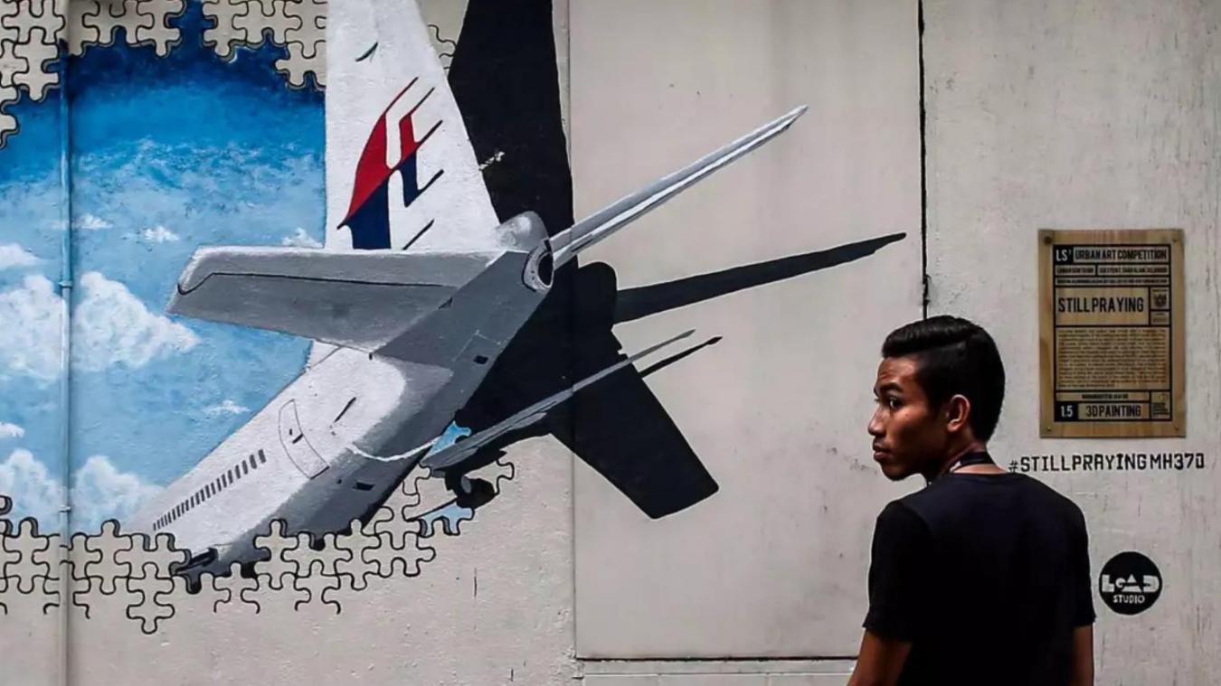 <p>Ein Mann steht vor einem Wandgemälde, auf dem das Verschwinden des Malaysia-Airlines-Flugs MH370 dargestellt ist.</p>