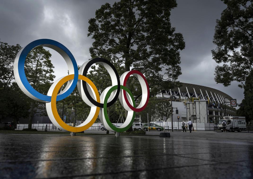 <p>Ein Monument mit der Darstellung der Olympischen Ringe leuchtet vor dem Nationalstadion in Tokio unter dunklen Wolken.</p>