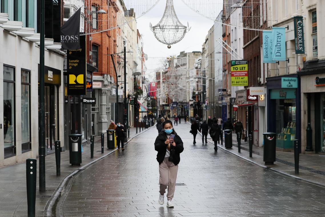 <p>Passanten mit Mund-Nasen-Bedeckungen gehen über die sonst geschäftige Grafton Street in Dublin.</p>