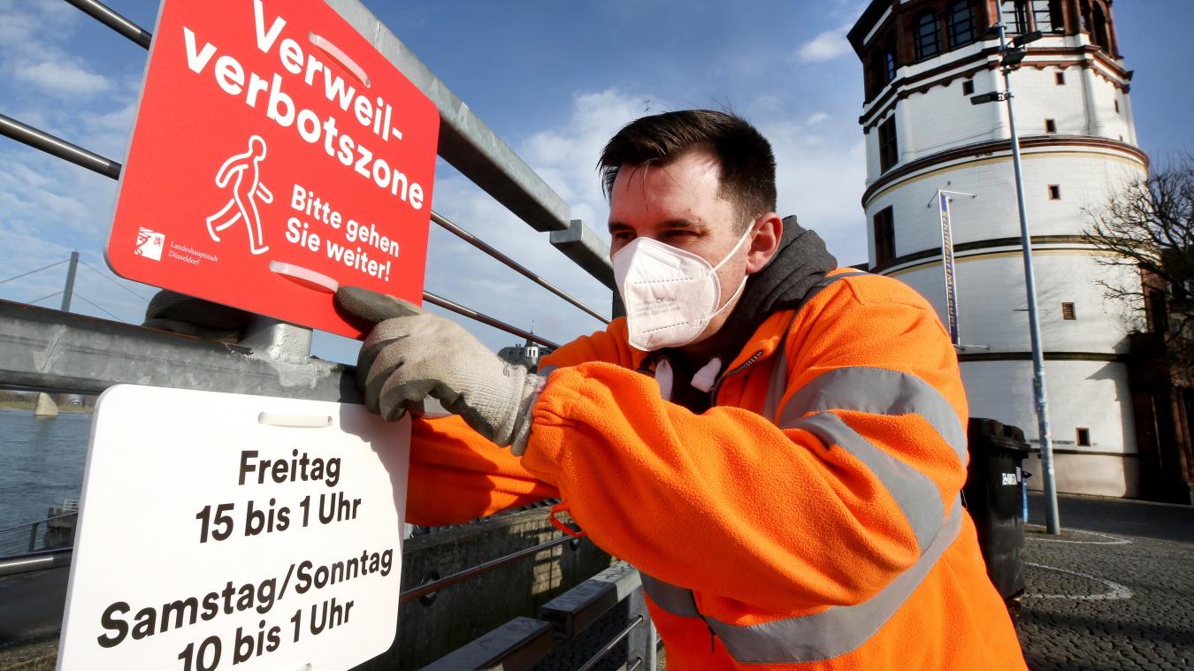 <p>Ein Mitarbeiter der Düsseldorfer Verkehrsbetriebe bringt ein Verbotsschild „Verweilverbotszone - Bitte gehen Sie weiter“ an.</p>