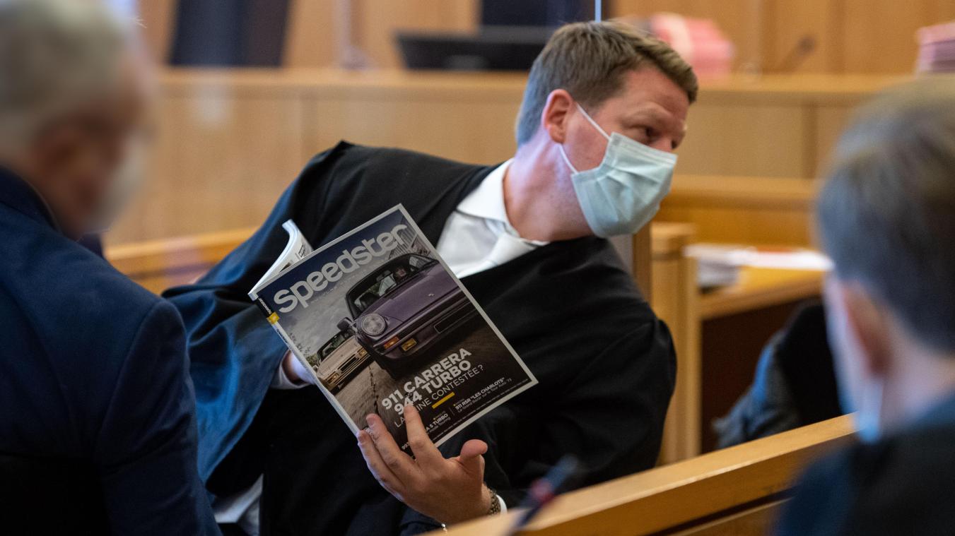 <p>Verteidiger Sören Gemmerich (Mitte) sitzt neben einem Angeklagten (links) auf der Anklagebank im Landgericht Aachen und zeigt Anwaltskollegen etwas in einer Porschezeitschrift.</p>