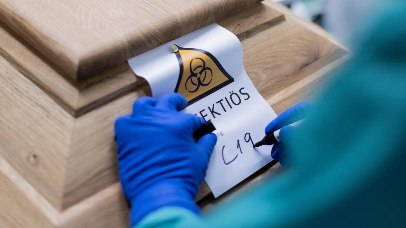 <p>Ein Bestattungsunternehmer schreibt „C19“ auf ein Schild mit dem Hinweis „Infektiös“ auf einen Sarg mit einem Verstorbenen, der an dem Coronavirus gestorben ist.</p>