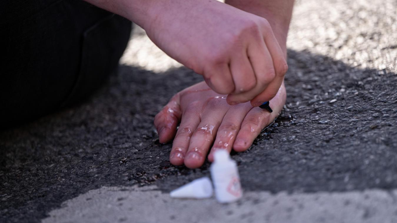 <p>Ein Klimaaktivist klebt seine Hand auf eine Fahrbahn.</p>