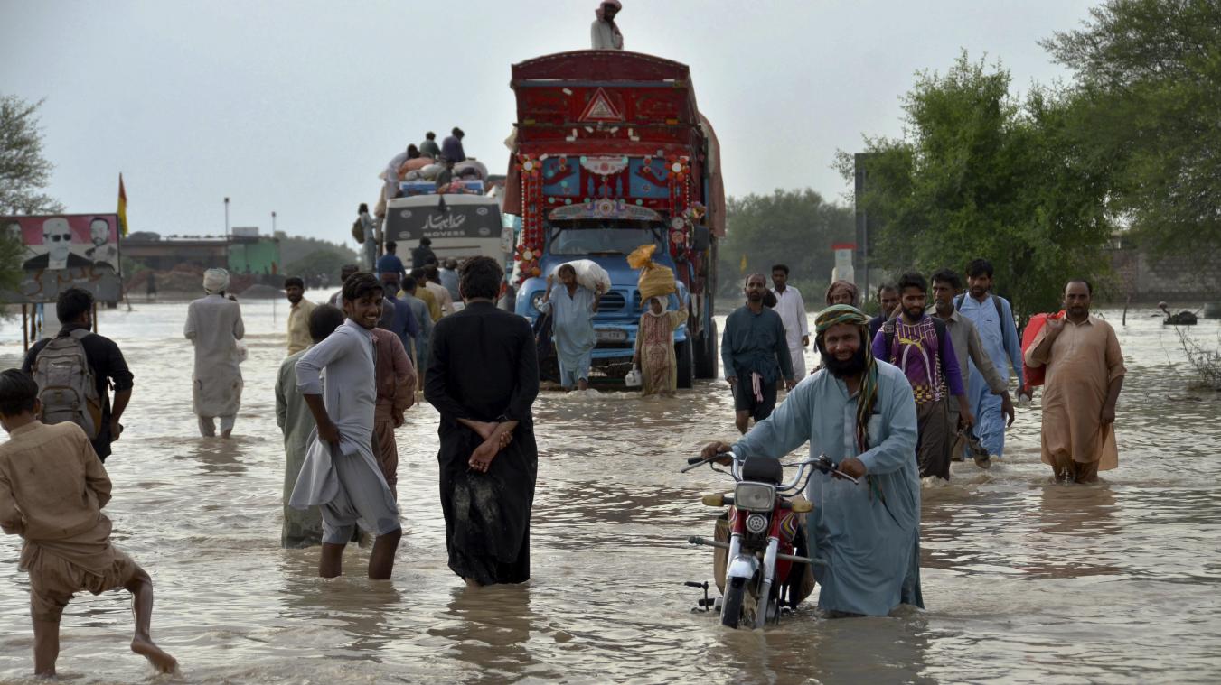 <p>Menschen gehen in der pakistanischen Stadt Nasirabad durch eine Straße, die durch schwere Monsunregenfälle überschwemmt wurde.</p>