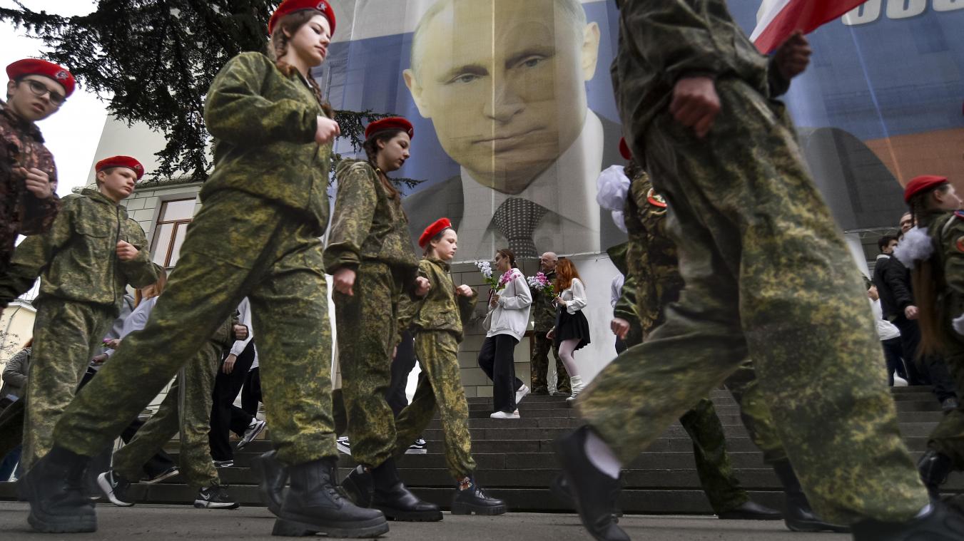<p>Uniformierte Jugendliche marschieren anlässlich einer Aktion zum neunten Jahrestag der Krim-Annexion an einem Bildnis des russischen Präsidenten Wladimir Putin vorbei.</p>