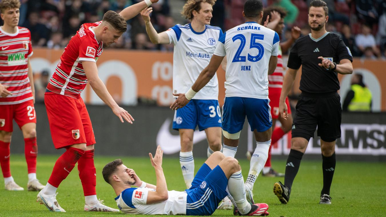 <p>Augsburgs Emirdan Demirovic (2.v.l.) entschuldigt sich, nachdem er Tom Krauß (unten) von Schalke im Gesicht getroffen hatte.</p>