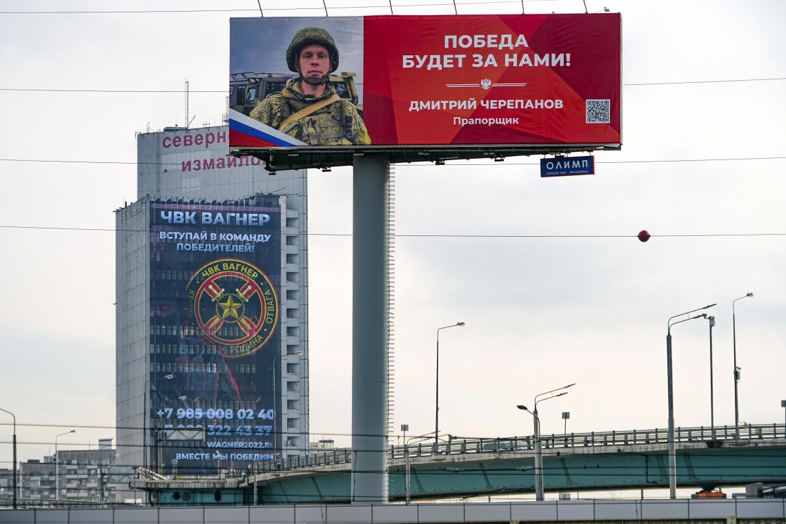 <p>An der Fassade eines Gebäudes ist ein Werbeschild zu sehen, auf dem für das Militärunternehmen Wagner (hinten) geworben wird und auf dem zu lesen ist „Schließen Sie sich dem Team der Sieger an“. Im Vordergrund ist ein Plakat mit einem Porträt des russischen Soldaten Dmitri Tscherepanow zu sehen, der für seinen Einsatz in der Ukraine ausgezeichnet wurde und der Aufschrift „Der Sieg wird unser sein“.</p>