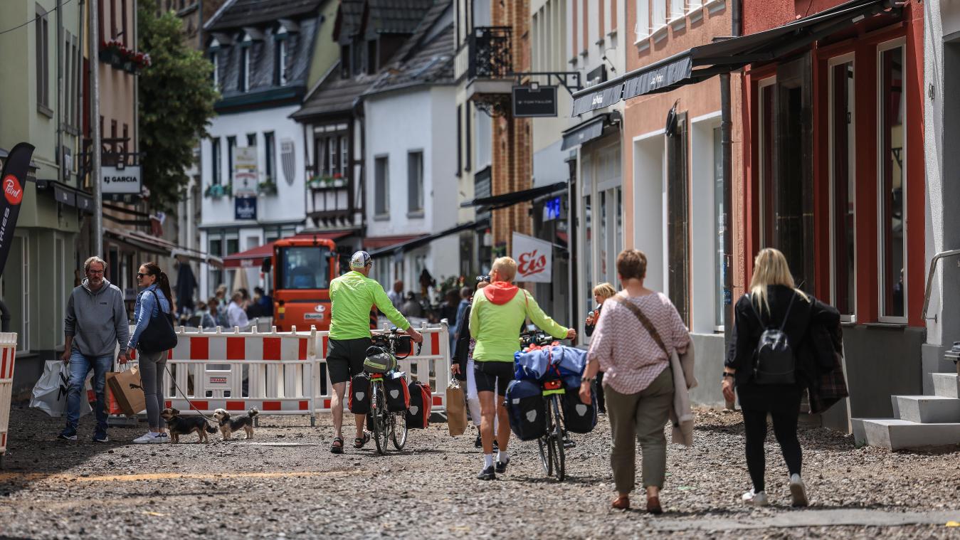 <p>Menschen gehen in Bad Münstereifel durch einen Teil der Fußgängerzone, die noch nicht fertiggestellt ist. Knapp zwei Jahre nach der Flutkatastrophe von 2021 sind in den betroffenen Orten immer noch die Folgen sichtbar.</p>