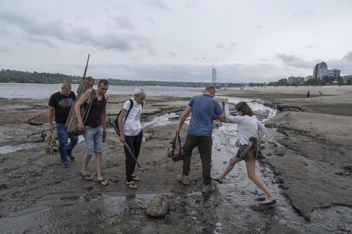 <p>Menschen gehen an einem Strand in Saporischschja spazieren, während das Wasser des Dnipro-Flusses nach der Explosion des Kachowka-Damms um mehr als vier Meter gesunken ist.</p>