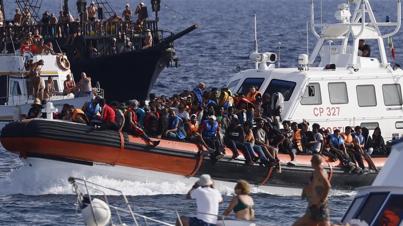 <p>Ein Boot der italienischen Küstenwache transportiert Migranten unter der Beobachtung einer Gruppe von Touristen. Die Ankunft Tausender Bootsmigranten in kurzer Zeit hat die Insel Lampedusa an ihre Grenzen gebracht.</p>
