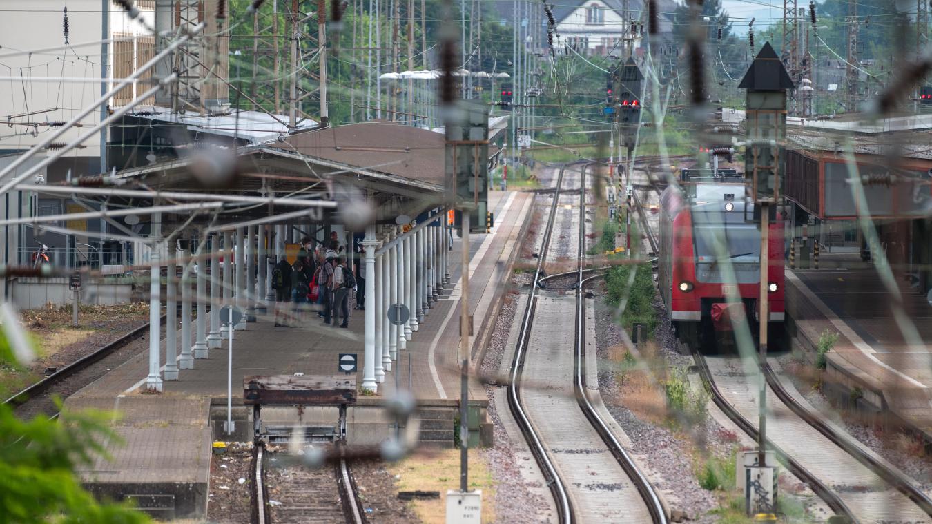<p>Menschen warten vormittags am Bahnsteig eines Gleises im Bahnhof Trier auf einen Zug.</p>