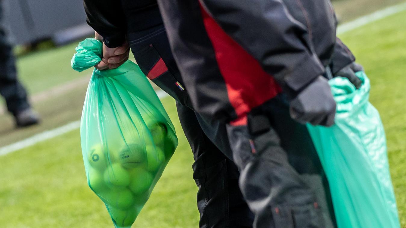 <p>Menschen sammeln von Fans des VfL Wolfsburg geworfene Tennisbälle.</p>