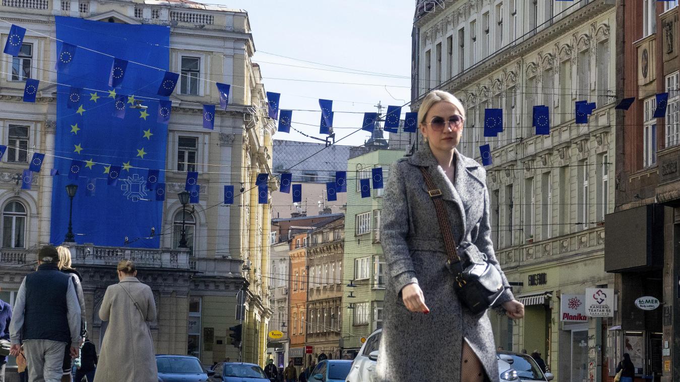 <p>Eine Frau geht unter den Flaggen der Europäischen Union in einer der Hauptstraßen von Sarajevo.</p>