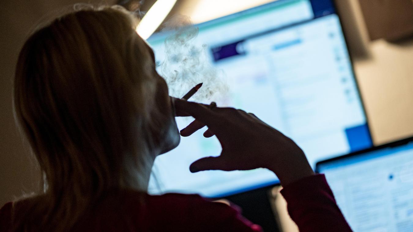 <p>Eine Frau raucht im HomeOffice vor ihren PC-Monitoren eine Zigarette.</p>