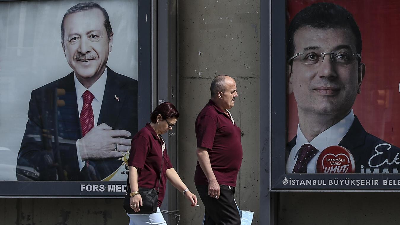 <p>Ein Mann und eine Frau gehen an Plakaten von Erdogan (links) und Imamoglu (rechts) vorbei.</p>