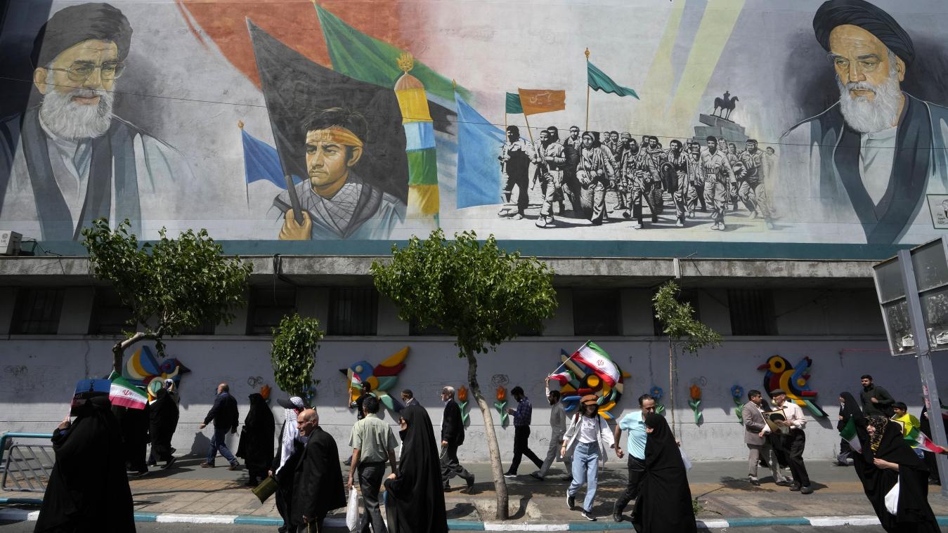 <p>Iranische Gläubige gehen an einem Wandgemälde vorbei, das den verstorbenen Revolutionsgründer Ayatollah Khomeini (rrechts), den Obersten Führer Ayatollah Ali Khamenei (links) und die paramilitärischen Basidsch-Kräfte zeigt.</p>