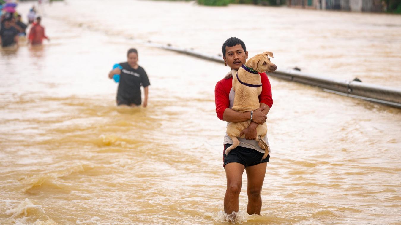<p>Ein Mann, der seinen Hund im Arm hält, watet durch die Fluten in einem Vorort von Hat Yai in der thailändischen Provinz Songkhla.</p>