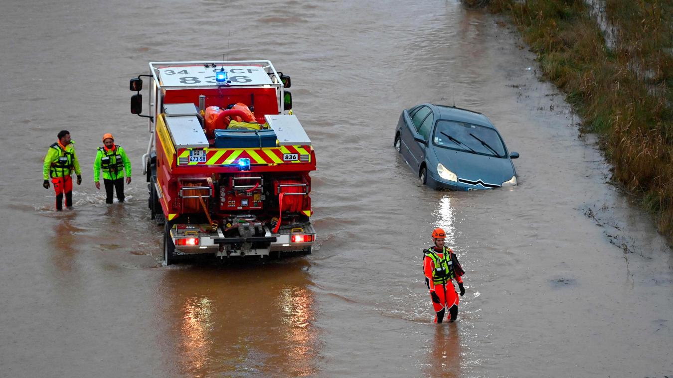 <p>Französische Rettungskräfte gehen an einem Auto vorbei, das am Ufer des Flusses Hérault steht, der nach starken Regenfällen über die Ufer getreten ist.</p>