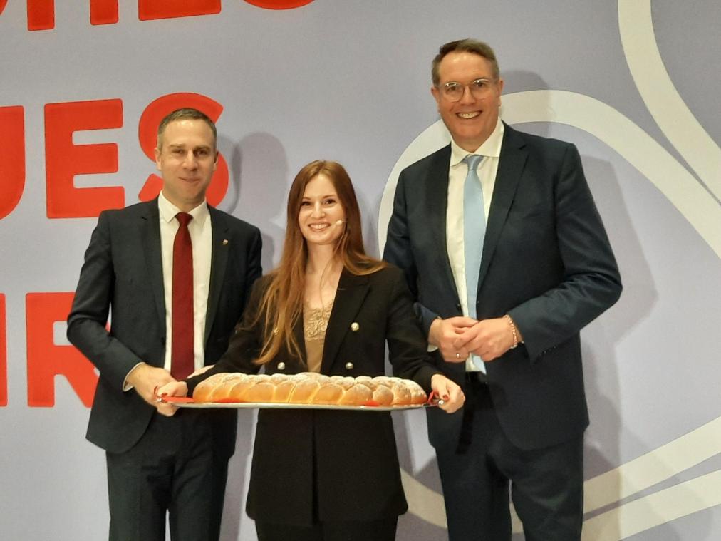 <p>Ministerpräsident Alexander Schweitzer (r.) und Moderatorin Lucy Webb überreichen dem örtlichen Landtagsabgeordneten Nico Steinbach (l.) einen Pfälzer Brezel.</p>