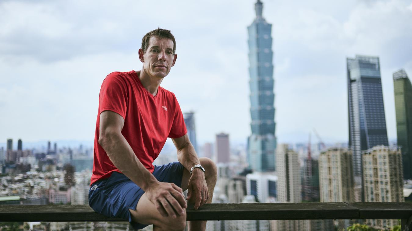 <p>Alex Honnold sitzt in Taipei auf einem Geländer vor Hochhäusern.</p>