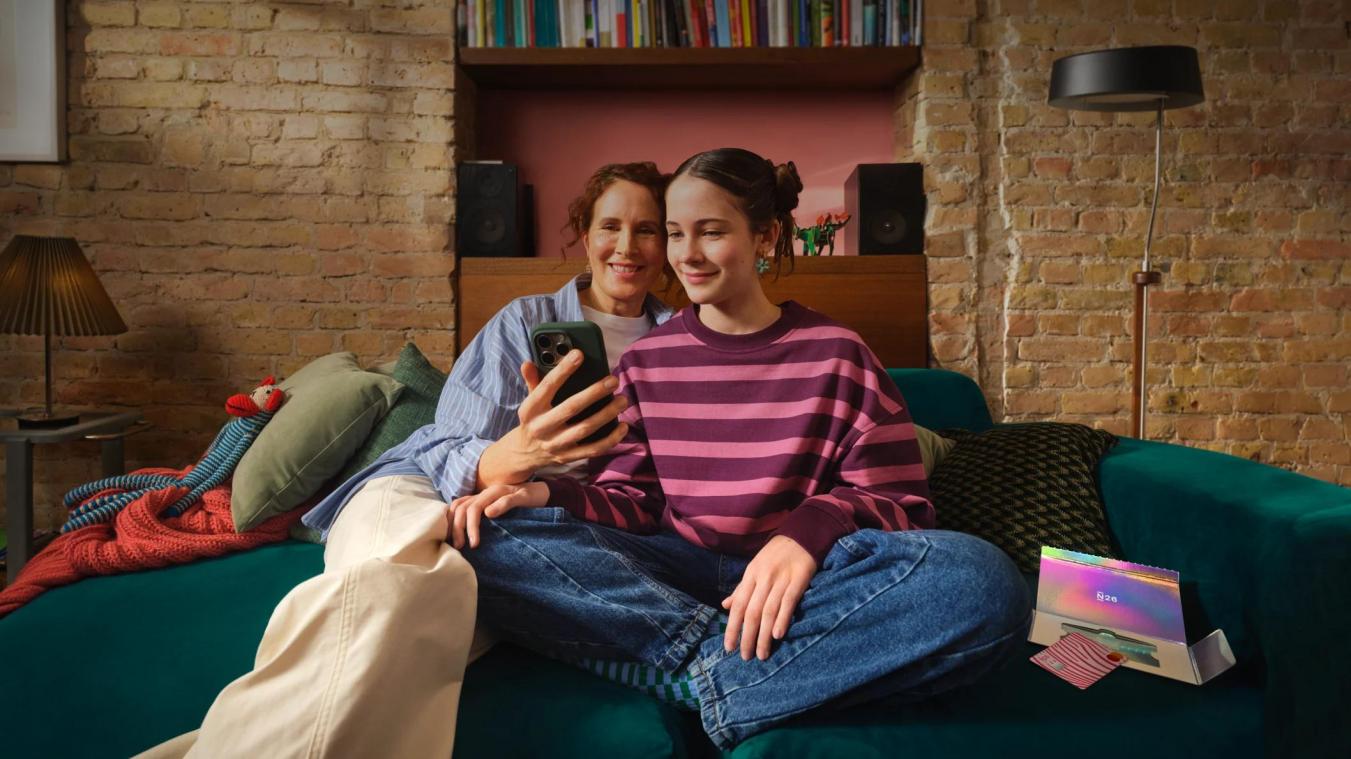 <p>Eine Mutter erklärt ihrer Tochter auf dem Sofa die Funktionender Kinder-Bankkarte von N26 – Ausgaben und Limits lassen sich per App in Echtzeit kontrollieren.</p>