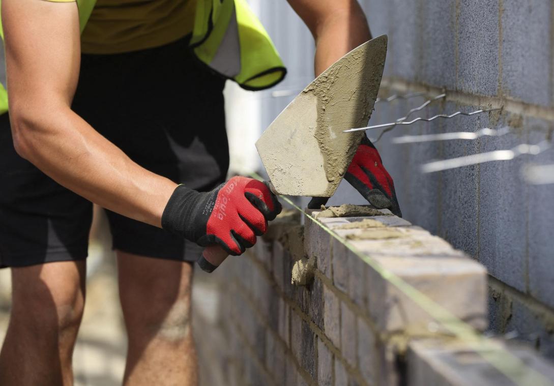 <p>Ein Bauarbeiter beim Mauern einer Wand: Fragen rund um Bauen, Flächennutzung und Zersiedelung stehen im Mittelpunkt der nächsten Bürgerversammlung in Ostbelgien, die sich mit einer nachhaltigen Raumordnung und der Zukunft von Infrastruktur, Natur und Dorfgemeinschaften befassen wird.</p>