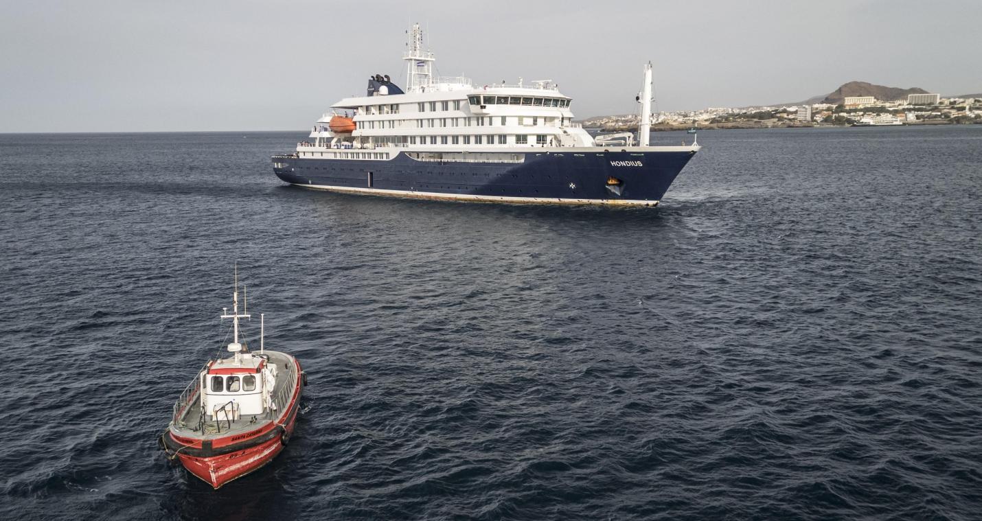 <p>Vor der Küste von Praia auf den Kapverden: Ein Boot steuert den Hafen an, während das Kreuzfahrtschiff „MV Hondius“ vor der Hauptstadt des Inselstaats vor Anker liegt.</p>