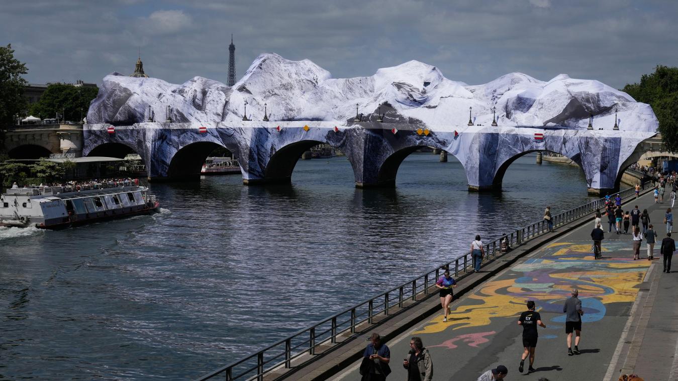 <p>Menschen spazieren entlang der Seine neben „The Pont Neuf Cave“, einer aufgeblasenen Kunstinstallation des französischen Straßenkünstlers JR</p>