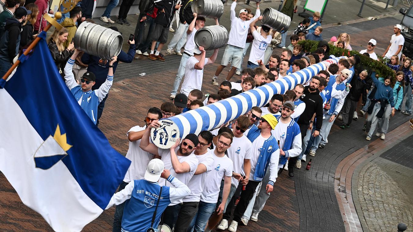<p>Mit vereinten Kräften tragen die St.Vither Junggesellen den blau-weißen Kirmesbaum durch die Straßen der Büchelstadt bis zum Festplatz.</p>