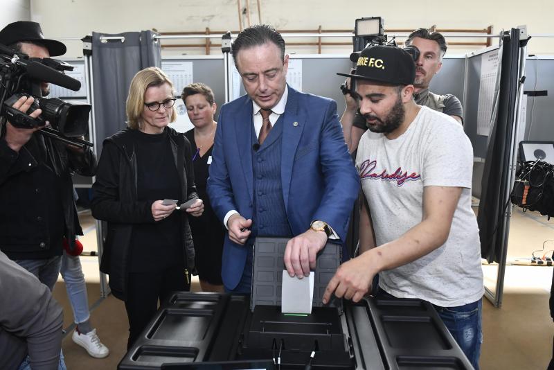 <p>Ein Wahlhelfer (rechts) schaut Bart De Wever an der Urne genau zu.</p>
