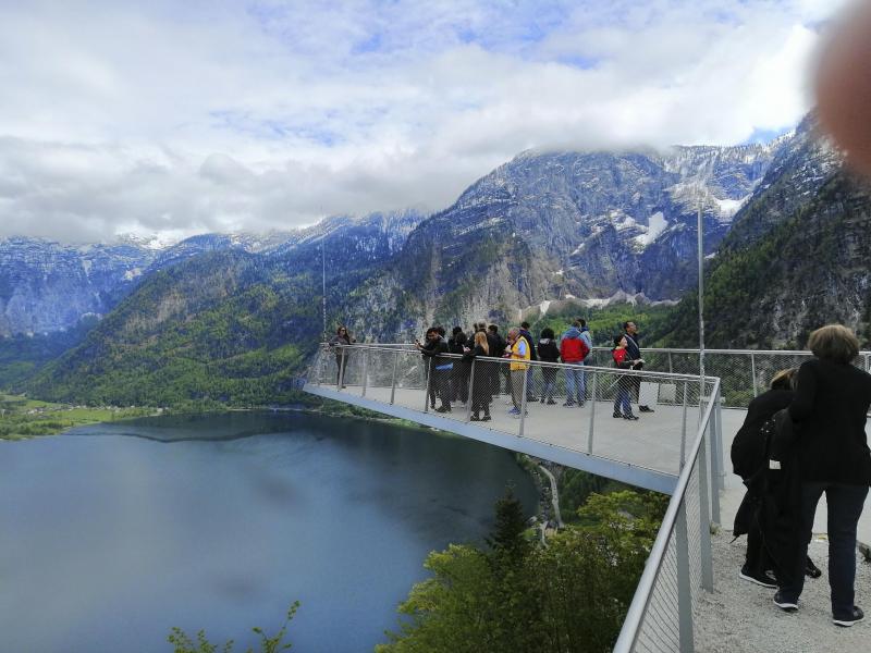 <p>Touristen stehen auf einer Aussichtsplattform über dem Hallstätter See.</p>