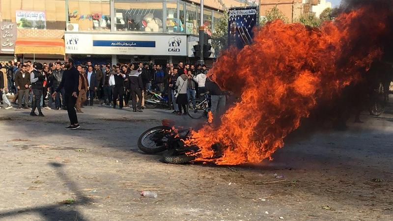 <p>Iransiche Demonstranten versammeln sich um ein brennendes Motorrad.</p>