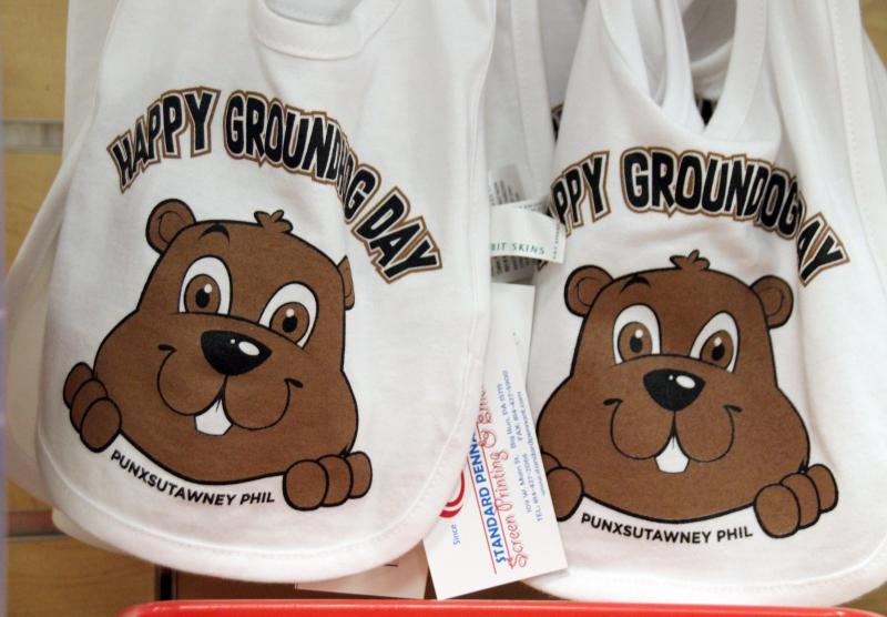 <p>Zwei Lätzchen mit einem aufgezeichneten Murmeltier und dem Schriftzug „Happy Groundhog Day“ hängen in einem Geschäft.</p>