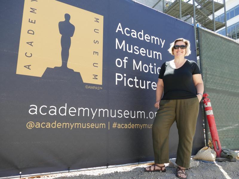 <p>Die deutsche Ausstellungskuratorin Jessica Niebel steht vor dem im Bau befindlichen Academy Museum of Motion Pictures neben einem Plakat.</p>