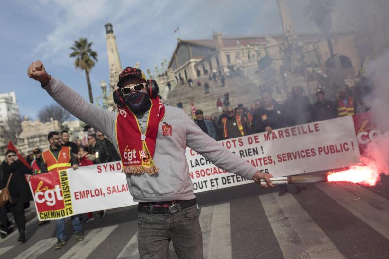<p>Frankreich, Marseille: Ein streikender Eisenbahner hält eine rote Rauchfackel.</p>