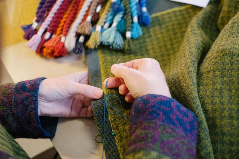 <p>Die Textildesignerin Anne-Susanne Gueler näht in ihrem Werkstattladen hand-werk“ an einer selbst gestrickten Jacke.</p>