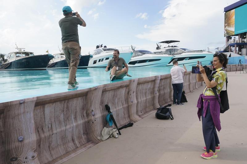 <p>Medienvertreter machen Fotos auf der gemalten Oberfläche, die Wasser simuliert, in der Nähe der auf dem Trockendock liegenden Yachten vor dem Hard Rock Stadium.</p>
