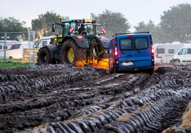 <p>Autos werden mit Hilfe eines Traktors auf das Gelände des Heavy-Metal-Festivals in Wacken durch den Schlamm gezogen.</p>