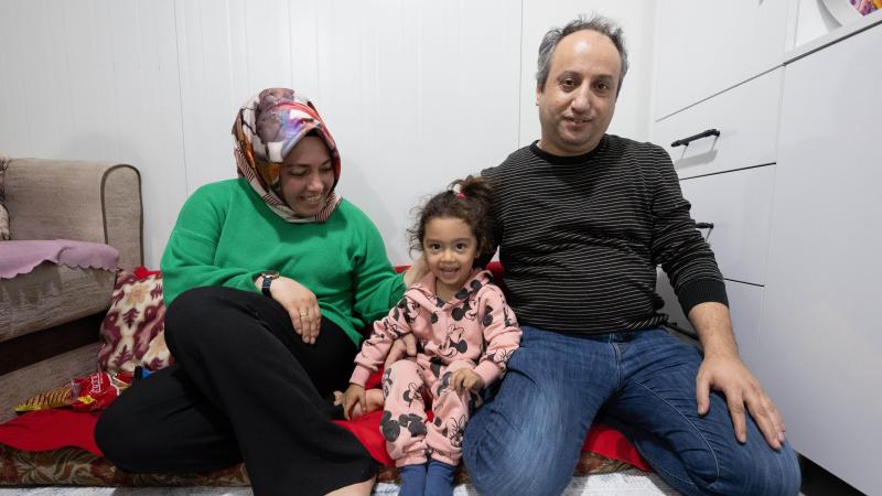 <p>Vater Mustafa und Mutter Hatice sitzen mit ihrer kleinen Fatmanur auf dem Boden ihres Wohncontainers, in dem die Familie nach dem Erdbeben untergekommen ist.</p>