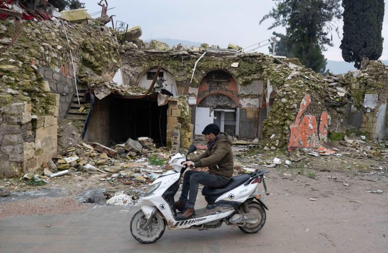 <p>Ein Mann fährt in Antakya mit seinem Mofa vor einem zerstörten Haus vorbei.</p>
