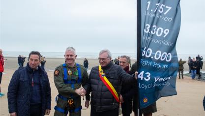 <p>Der Bürgermeister von Koksijde und ein Besatzungsmitglied des Sea King stellen am Strand eine Gedenkflagge auf, auf der die Leistungen des Rettungshubschraubers vermeldet sind.</p>