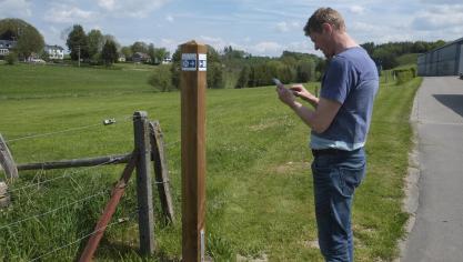 <p>Projektleiter Dany Heck vor einem der 500 Pfosten, die in der Gemeinde Burg-Reuland den Weg weisen: Das System funktioniert mit App, aber auch auf analoge Art und Weise.</p>