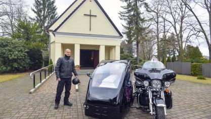 <p>Ingo Rauf neben seinem Motorrad der Marke „Harley Davidson“ mit Beiwagen und Sarg</p>