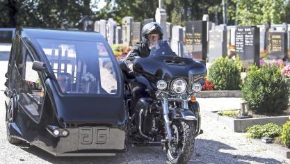 <p>Bestatter Wolfgang Frisch fährt mit seinem Bestattungsmotorrad, über einen Friedhof. Mit der Harley-Davidson können Motorradfans im Sarg oder in der Urne ihre letzte Reise antreten.</p>