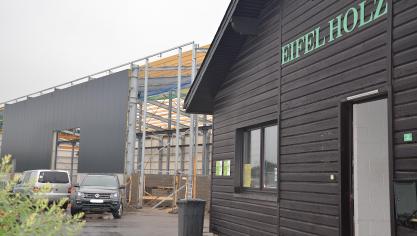 <p>Seit 1989 ist das Unternehmen Eifel-Holz auf Morsheck angesiedelt. Nach der mühsam erkämpften Erteilung einer neuen Globalgenehmigung konnte im Frühjahr der Bau einer neuen Produktionshalle (im Hintergrund) beginnen.</p>