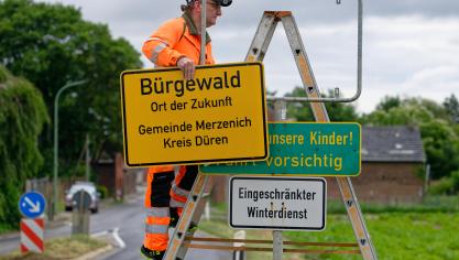 <p>Ein Mitarbeiter von Straßen NRW bringt ein neues Ortsschild am Ortseingang des Braunkohledorfes Morschenich an. Ab jetzt heißt der Ort Bürgewald.</p>