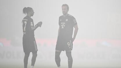 <p>Die Bayern-Spieler Kane (r.) und Olise im Kölner Pyro-Nebel</p>